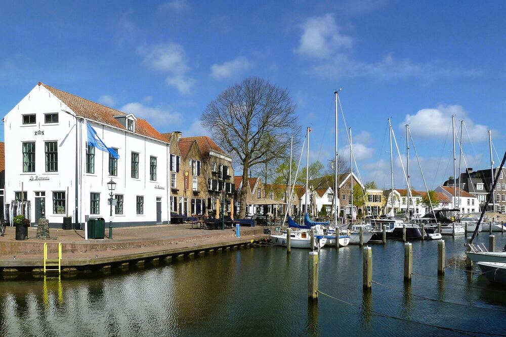 Wit monumentaal pand aan de binnenhaven van Middelharnis met afgemeerde zeilboten langs de kade